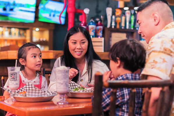 Una familia cenando en un restaurante con un bar al fondo.