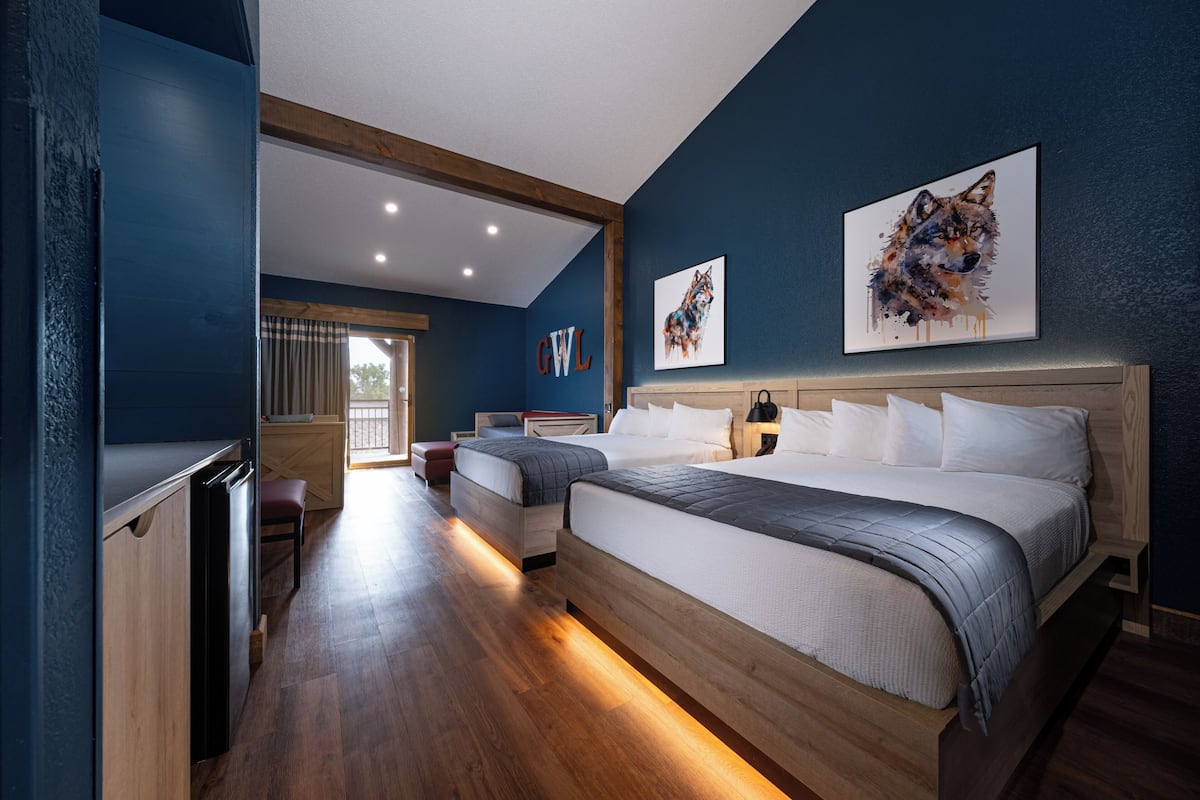 A bedroom with two beds, a wooden floor, and artwork on the walls.
