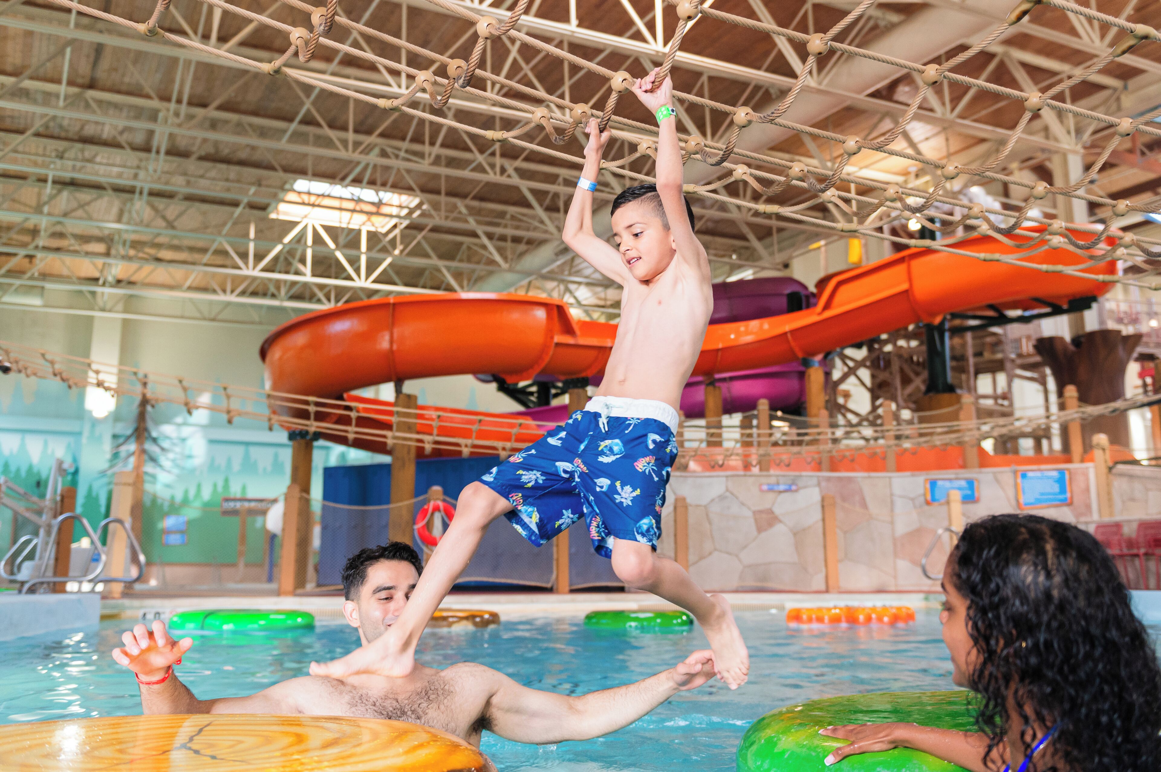 Um parque aquático coberto com toboáguas, piscina e estrutura de escalada em cordas.