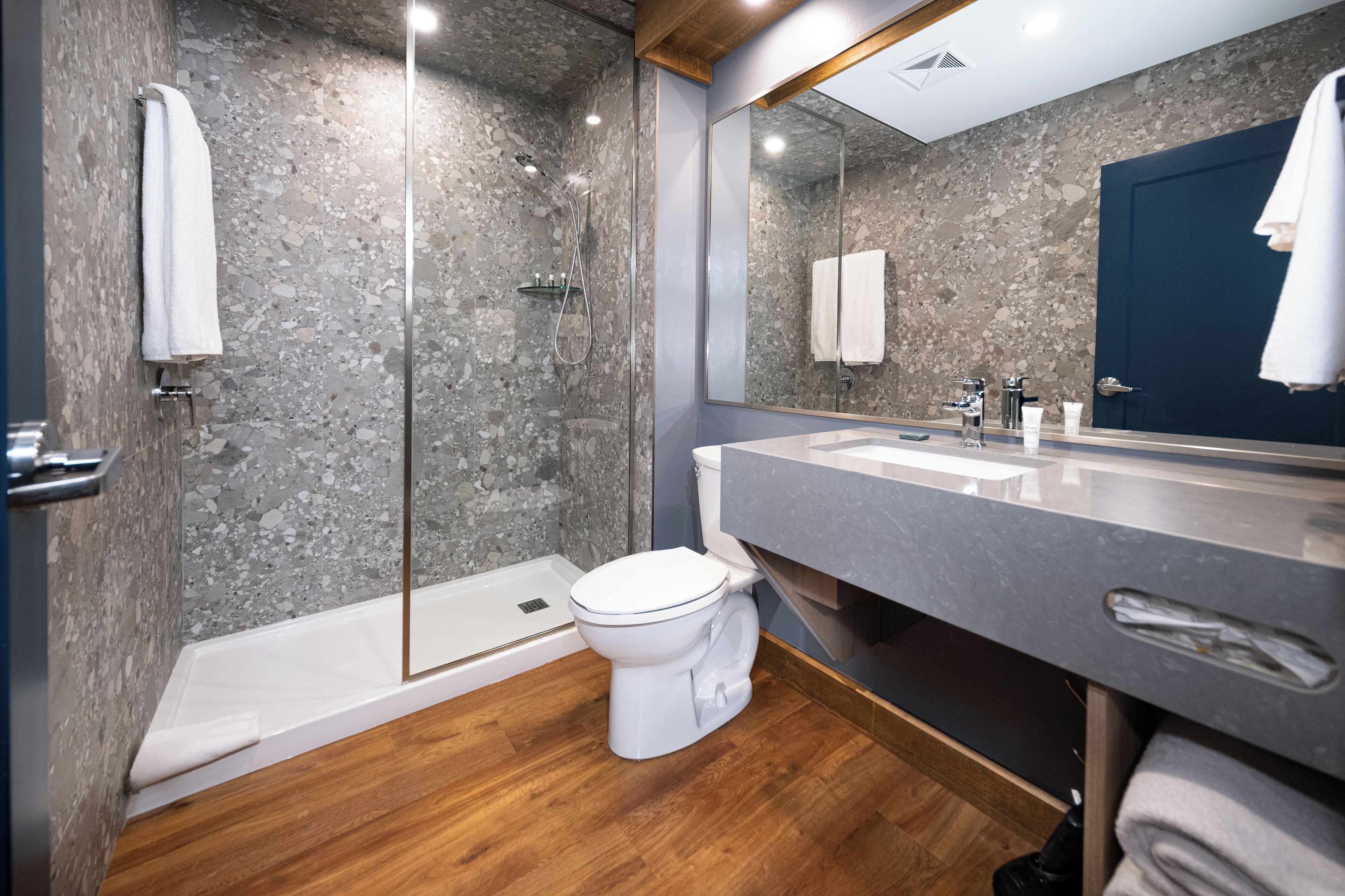 A modern bathroom with a shower, toilet, and sink.