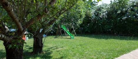 A grassy area with a playground featuring a slide and swings.