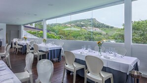 Un restaurante con mesas dispuestas para comer, amplias ventanas que ofrecen vistas a un paisaje verde.