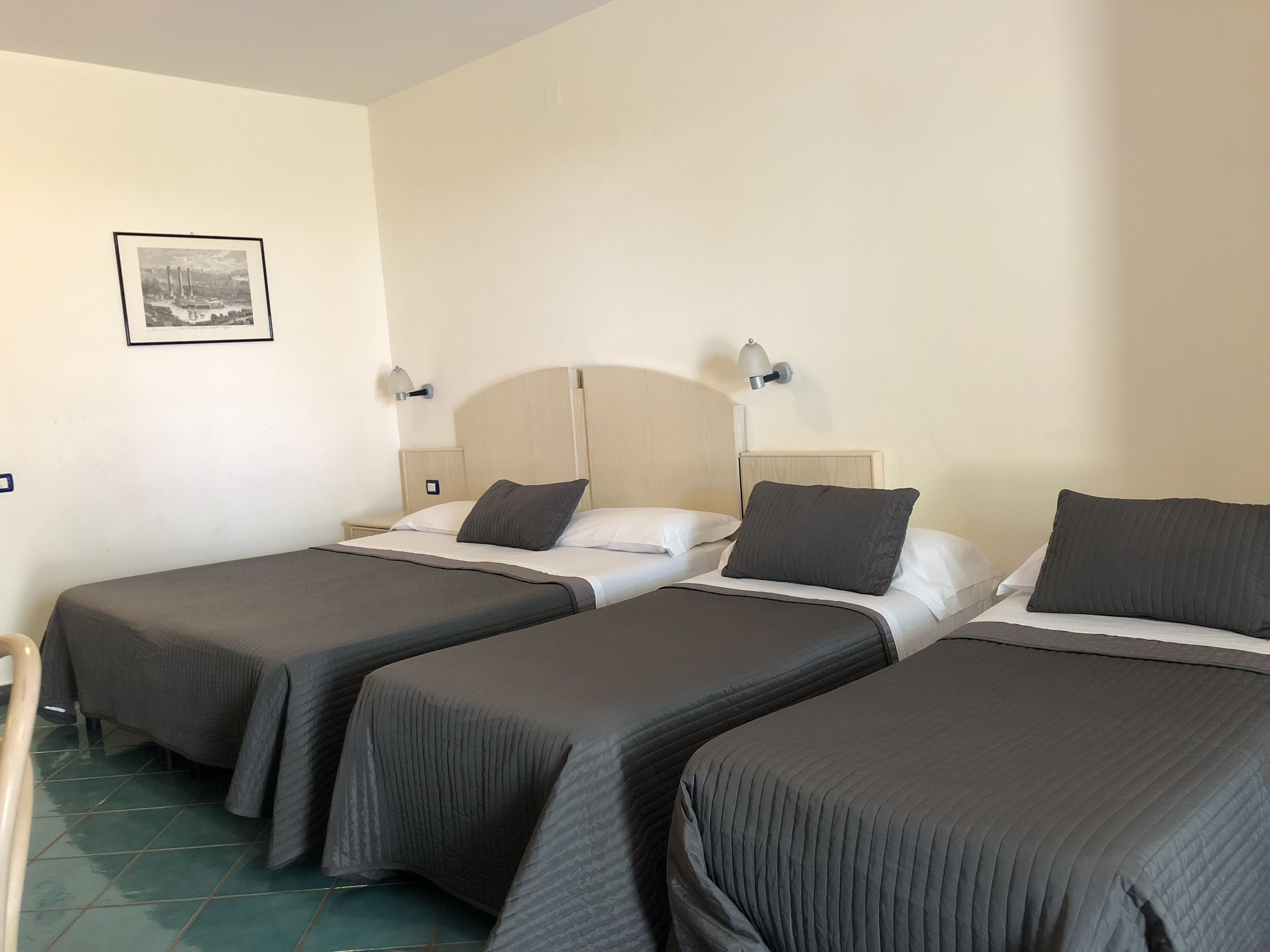 Ein Hotelzimmer mit zwei Einzelbetten, jeweils mit Kopfstütze, Nachttischen und Wandleuchten.