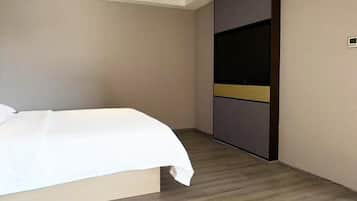 Una habitación de hotel con una cama, un armario y un televisor de pantalla plana.