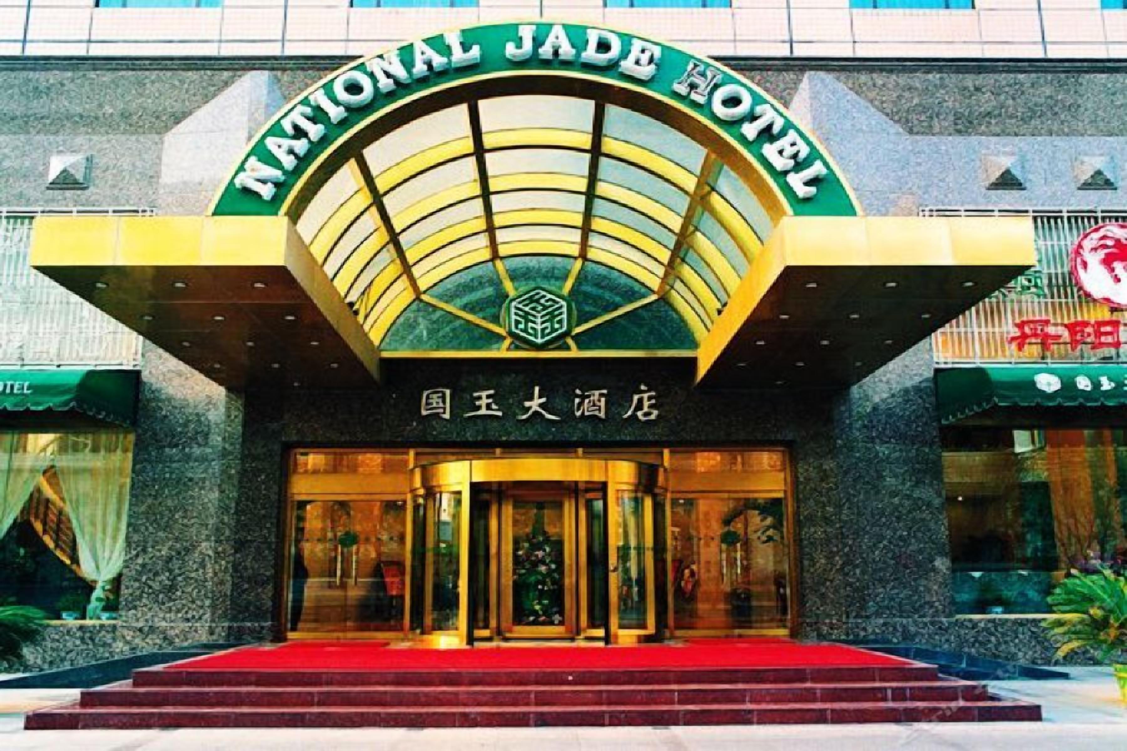 Der Eingang des National Jade Hotels mit einem markanten Bogen und einer roten Teppichvorrichtung zu den Türen.