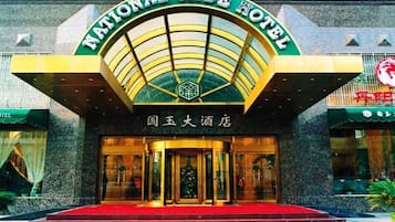 Der Eingang des National Jade Hotels mit einem markanten Bogen und einer roten Teppichvorrichtung zu den Türen.