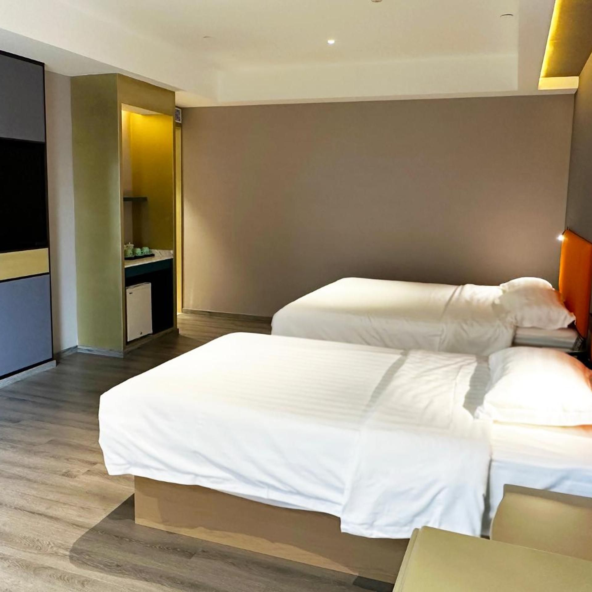 Hotellihuone, jossa on sänky, yöpöytä ja sisäänrakennettu vaatekaappi.