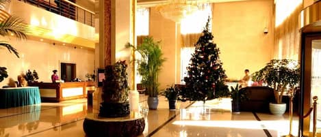 A lobby with a reception desk, a Christmas tree, and a large chandelier.