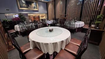 Ein Restaurant mit runden Tischen, braunen Ledersesseln und einem blauen Vorhang darüber.