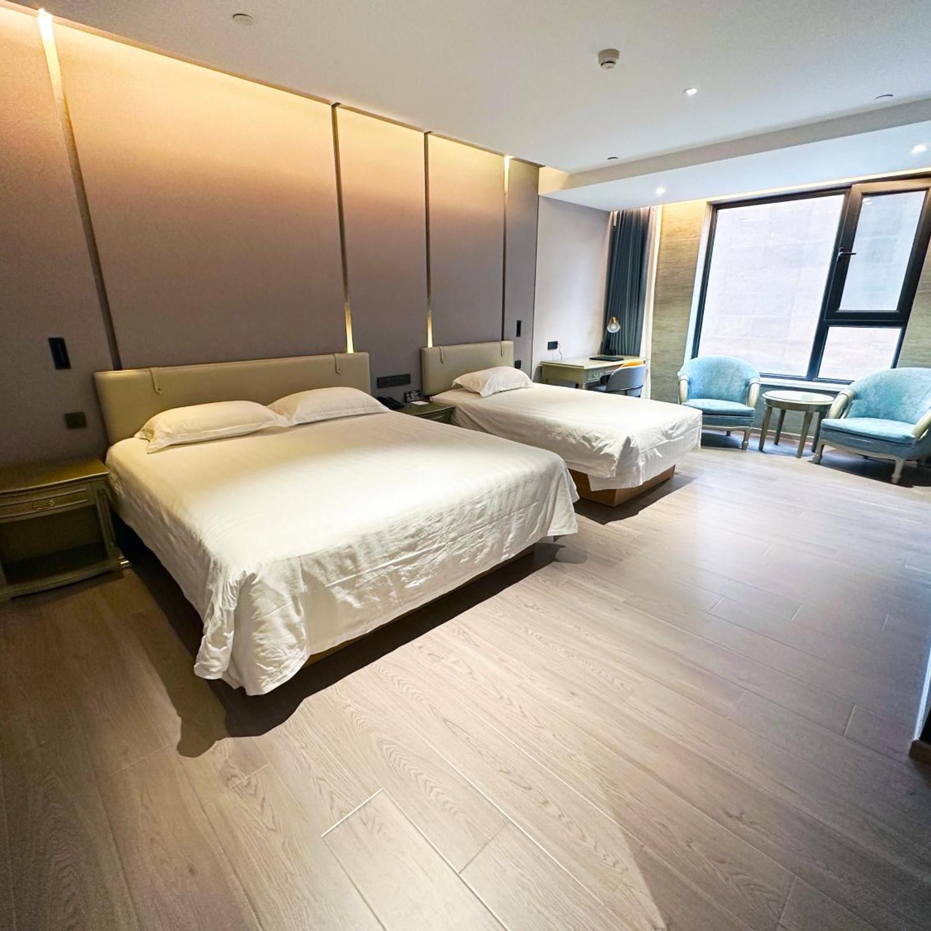 A hotel room with two beds, a desk, and a chair.