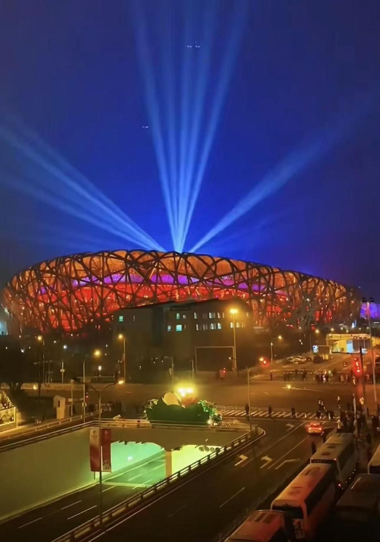 A stadium with a distinctive roof structure and a large, illuminated entrance.