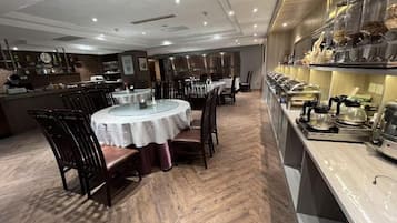 Restaurante com mesas redondas, cadeiras e um balcão com equipamentos de cozinha.
