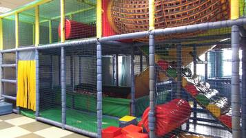 Children can play safely in this enclosed play area with tunnels, slides, and soft surfaces.