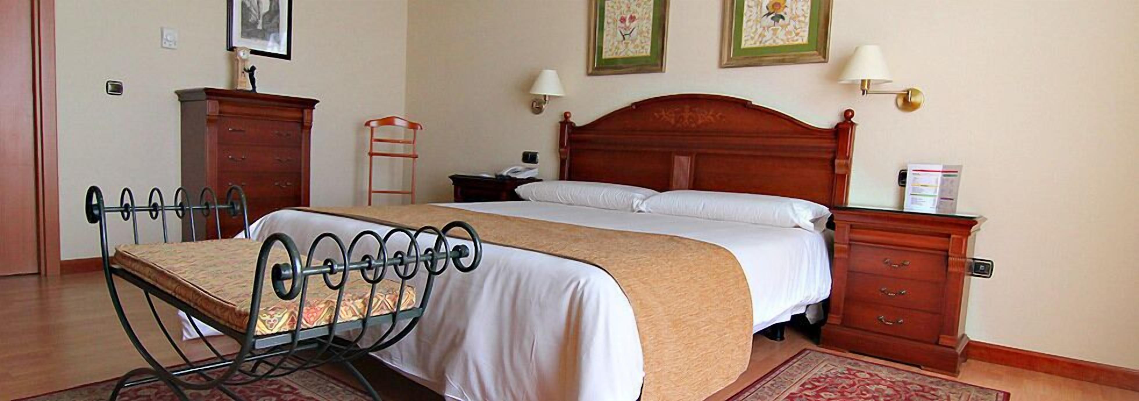 Un dormitorio ordenado con cama, mesitas de noche, armario y una silla.