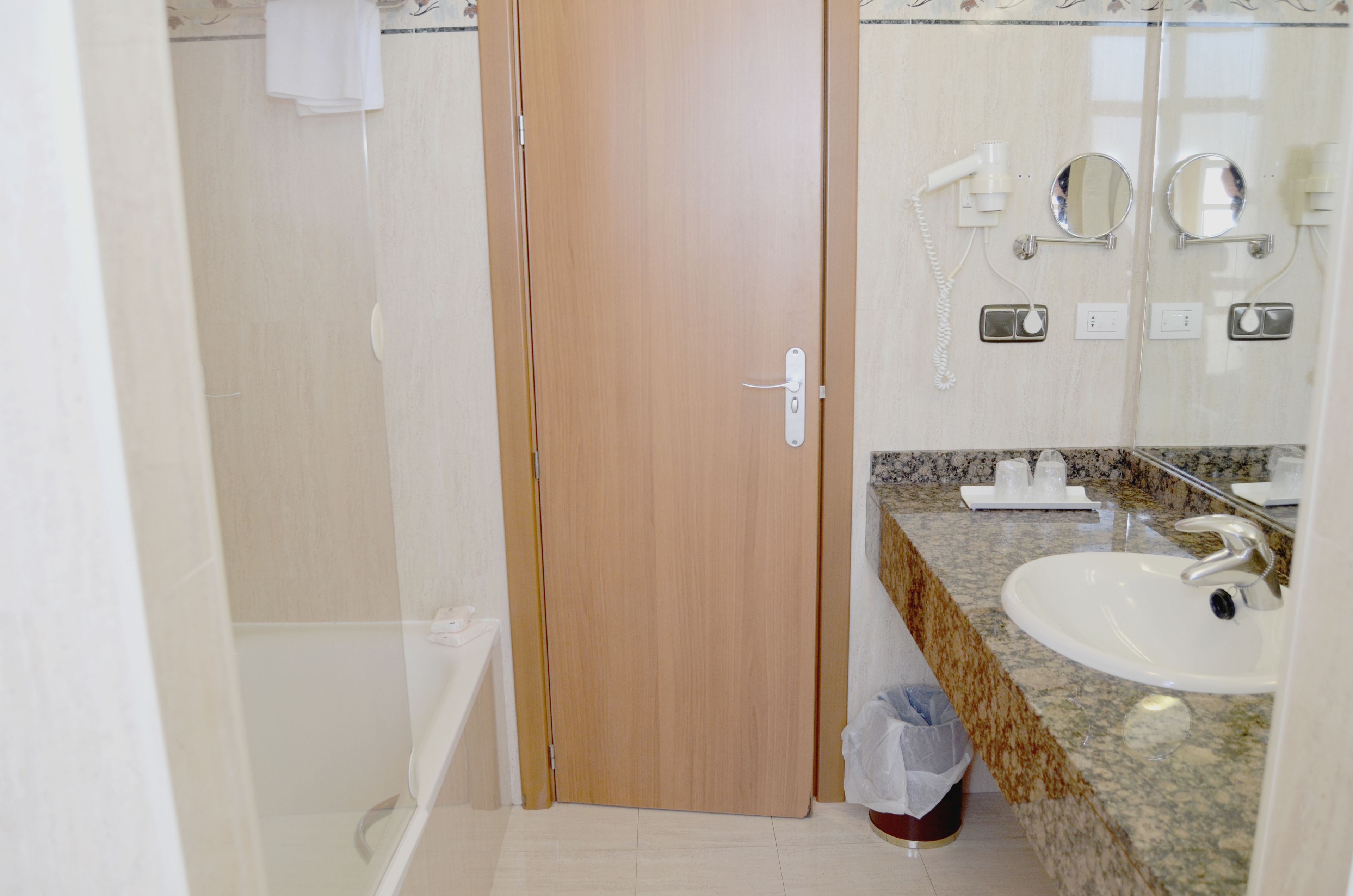 Une salle de bain avec une porte en bois, un lavabo et un miroir.
