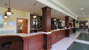 Zona de bar con mostradores de madera, luces colgantes y suelo de baldosas.