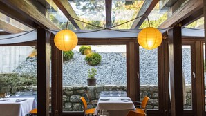 An outdoor dining area with tables set for two, wooden beams, and hanging paper lanterns. - Hotel Río Bidasoa (Hondarribia)