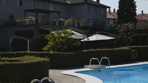 A swimming pool with a curved edge, metal ladders, and a white umbrella. - Hotel Río Bidasoa (Hondarribia)