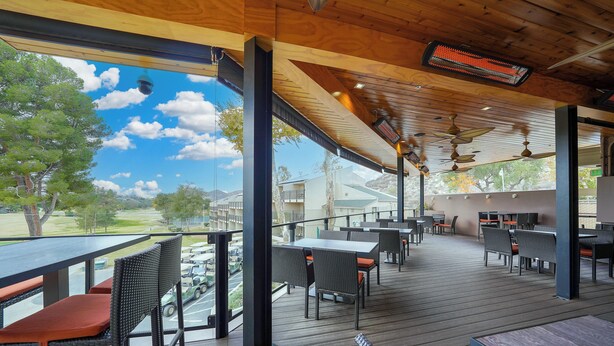 An outdoor patio with wooden flooring, wicker chairs, and tables. - San Vicente Golf Resort (Ramona)