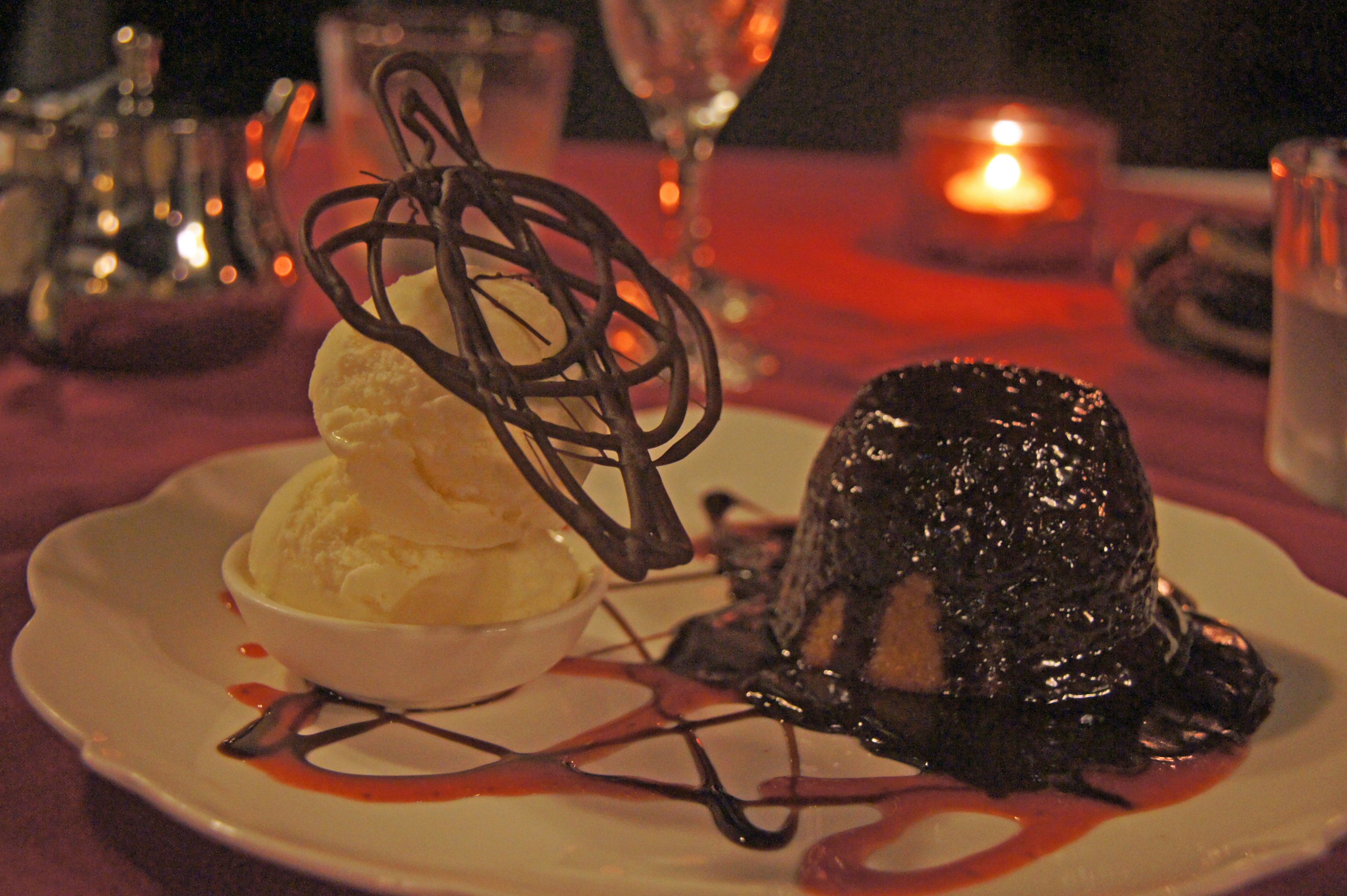 Un plato de postre con un dulce de chocolate y una porción de helado.