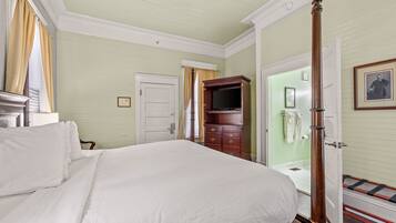 Une chambre avec un grand lit, une commode en bois, un téléviseur et une porte menant à la salle de bain.