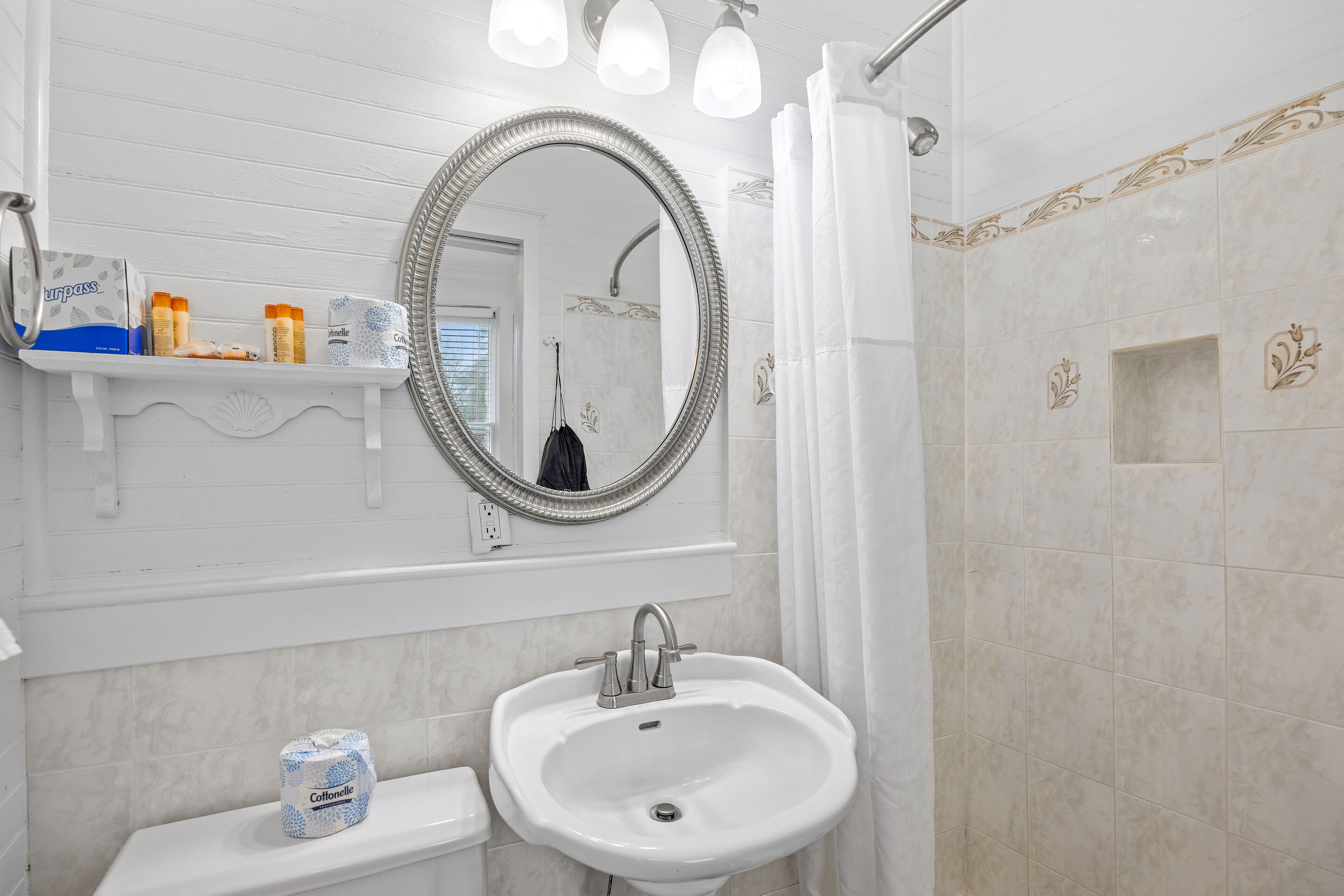 A bathroom with a sink, mirror, and shower curtain.
