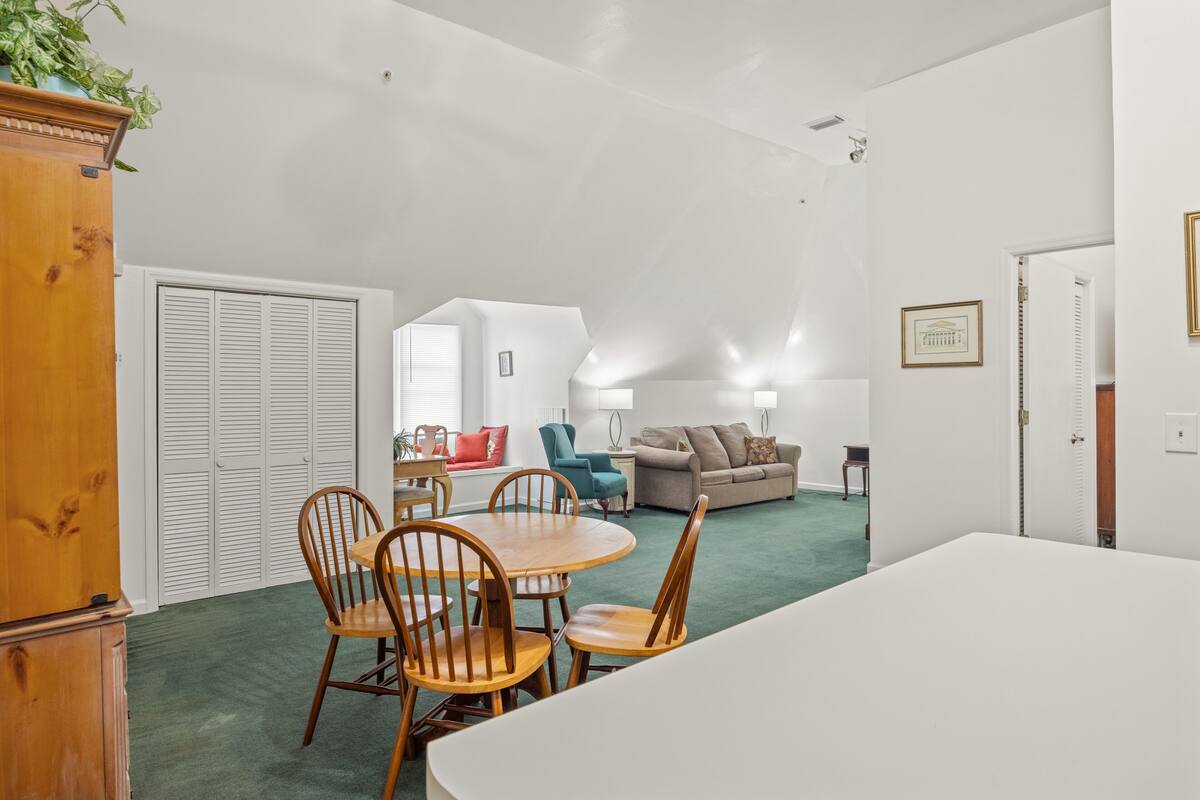 A spacious living room with a dining area, a sofa, and a lamp.