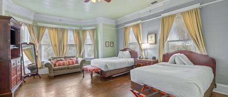 A room with a bed, a sofa, a wooden dresser, and a ceiling fan.