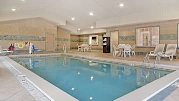 Relax by the rectangular pool surrounded by a deck with lounge chairs and a table.