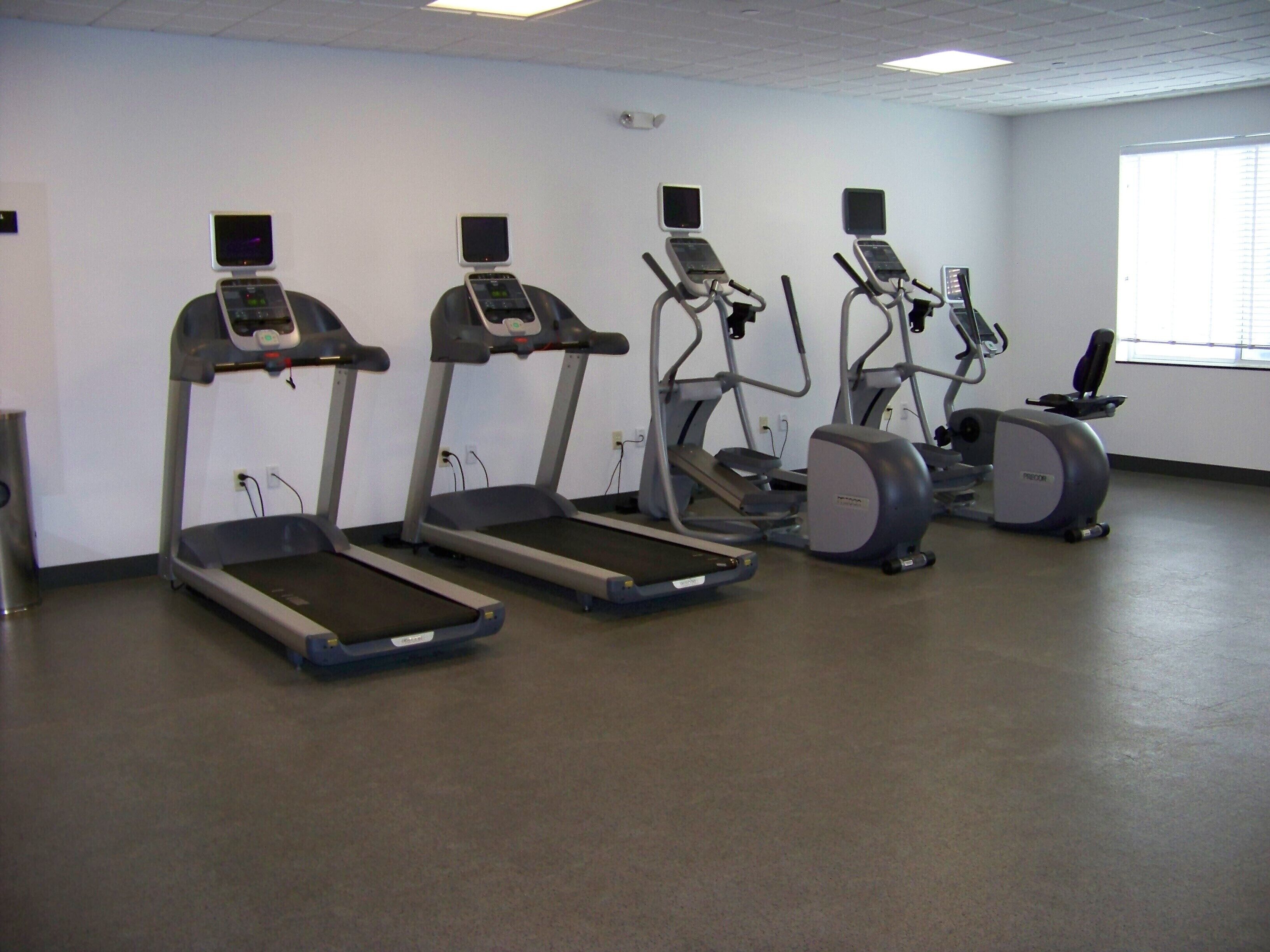 A gym with four treadmills, one elliptical, and one stationary bike.