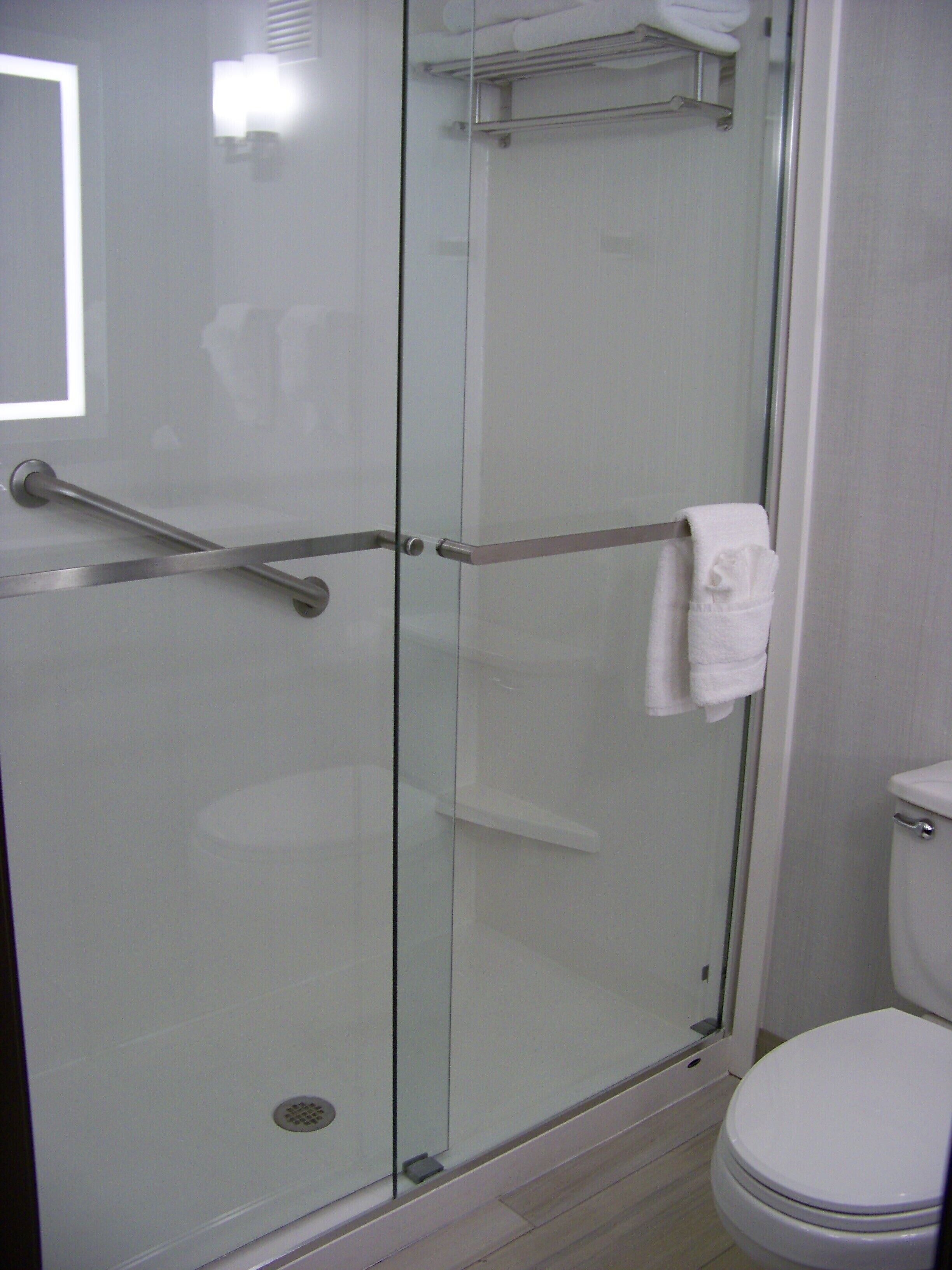Un baño moderno con ducha de vidrio, inodoro blanco y toallero.
