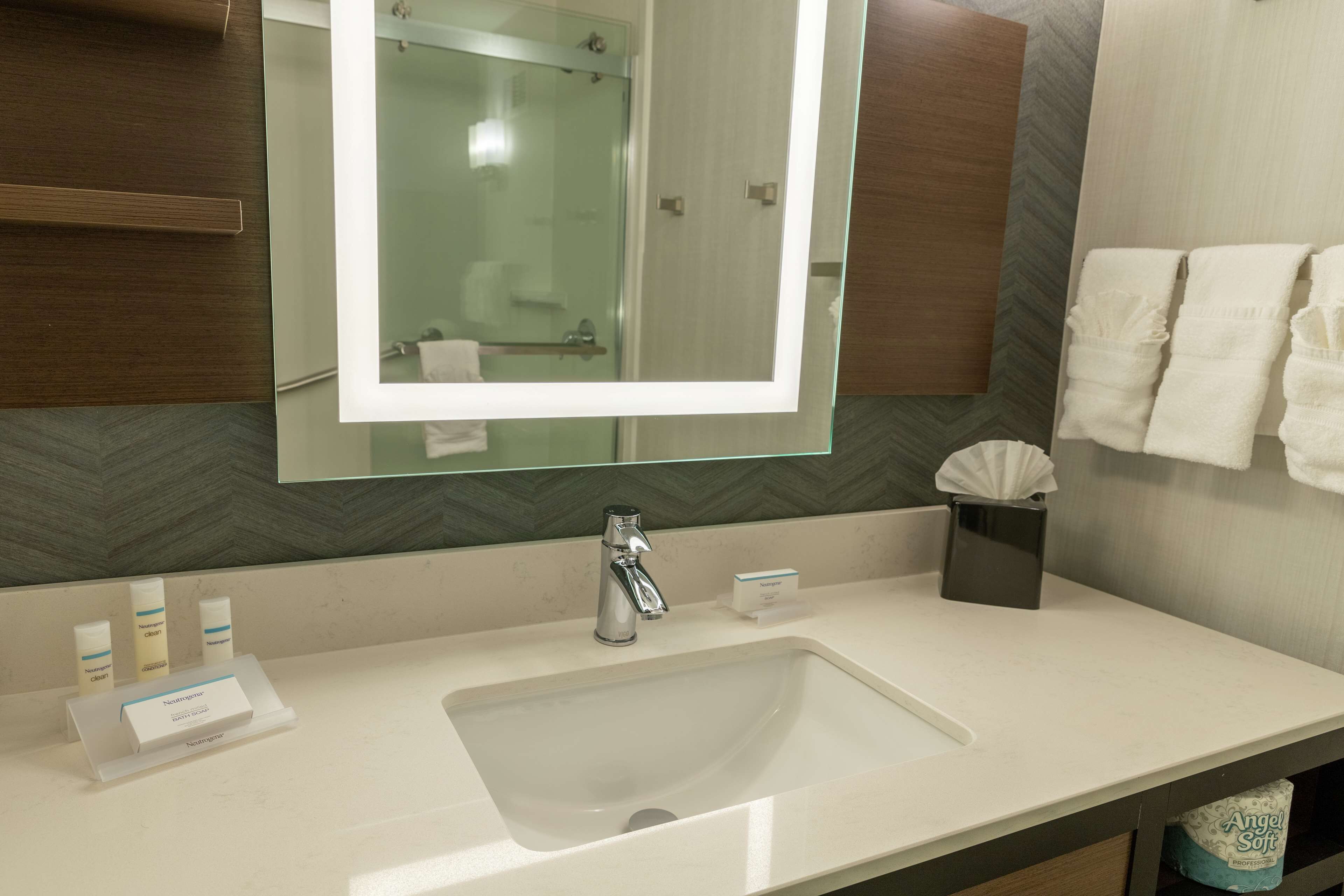 Un baño con un espejo grande, un lavabo y un perchero para toallas.