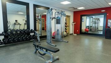 Un gimnasio con equipo de ejercicio, una cinta de correr y un espejo montado en la pared.