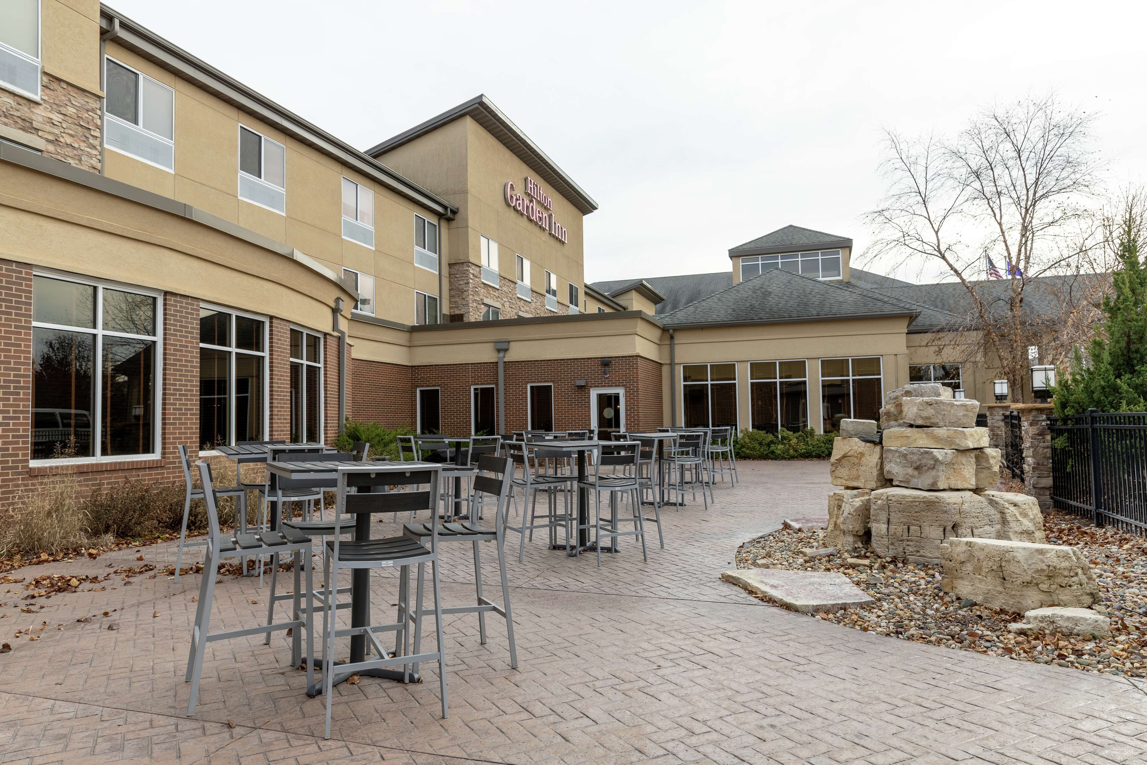 A hotel with outdoor seating and a stone feature.