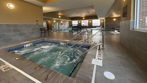 A large indoor swimming pool with a wooden ceiling and tiled walls. - Hilton Garden Inn Des Moines West (West Des Moines)