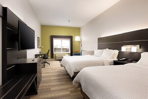 Habitación de hotel con dos camas, un escritorio, un televisor y una ventana.