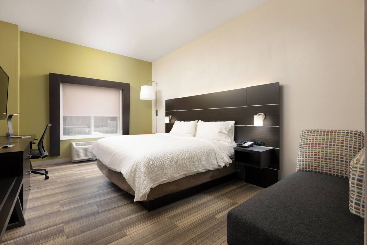 Ein Hotelzimmer mit einem großen Bett, Nachttischen, einem Schreibtisch und einem Sessel.