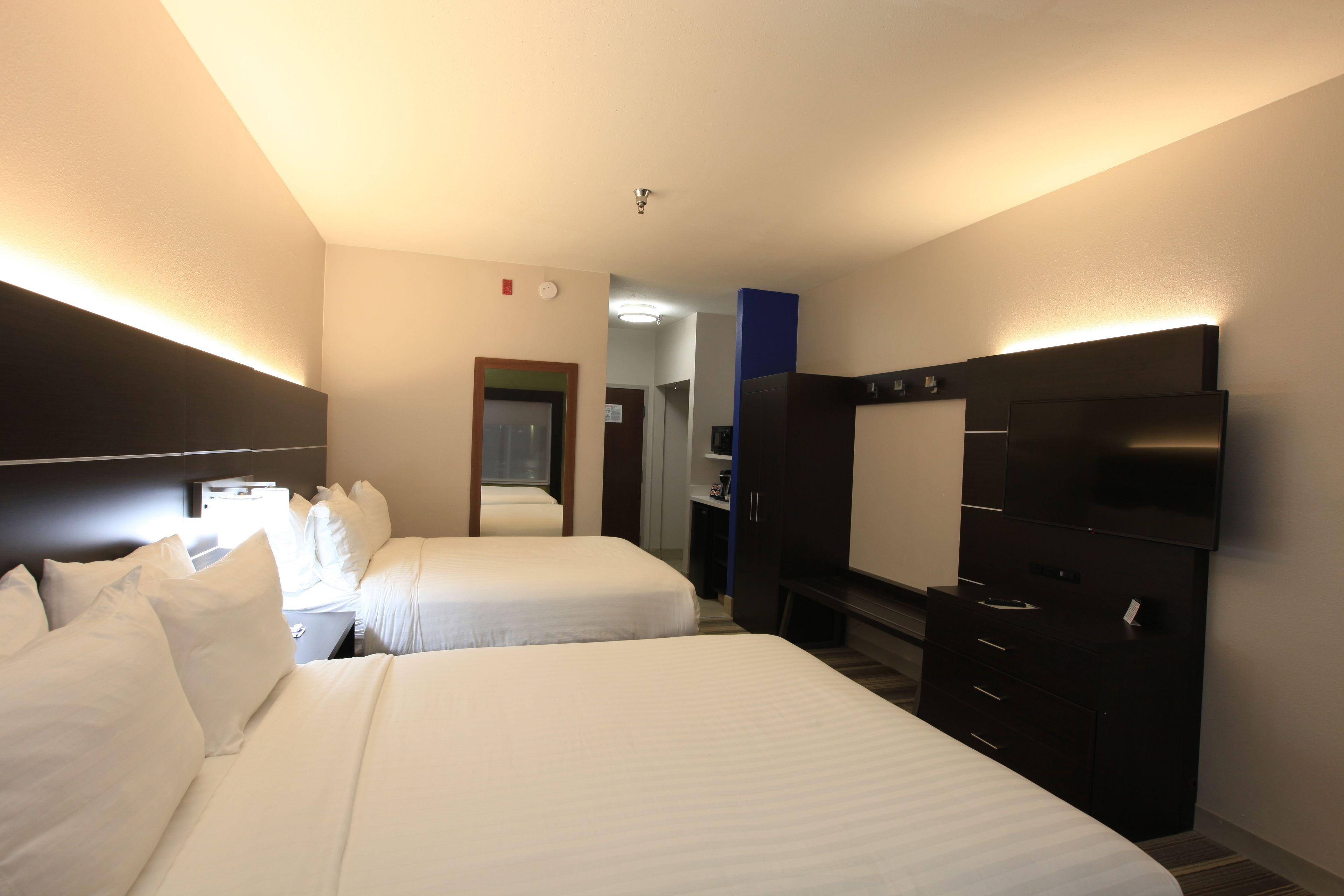 A hotel room with two beds, a flat-screen TV, a dresser, and a mirror.