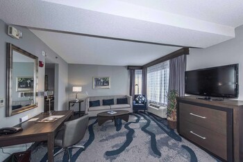 Relax in a spacious room with a large flat-screen TV, comfortable sofa, and a desk for work. at DoubleTree by Hilton North Charleston - Convention Center