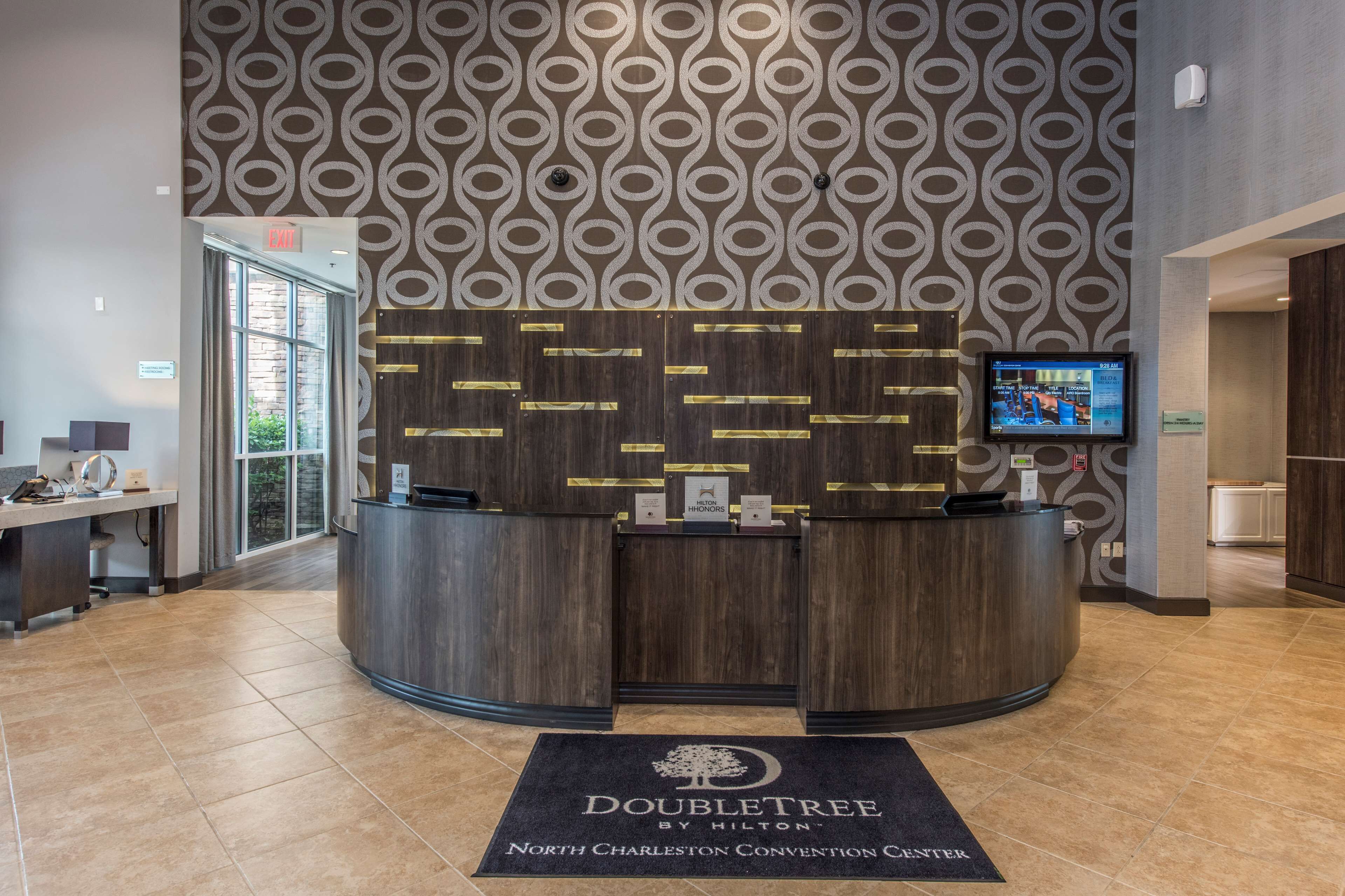 Una reception con uno schermo, un cartello con la scritta 'Doubletree by Hilton' e un segnale a terra con la scritta 'North Charleston Convention Center'.