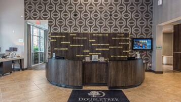 Una reception con uno schermo, un cartello con la scritta 'Doubletree by Hilton' e un segnale a terra con la scritta 'North Charleston Convention Center'.