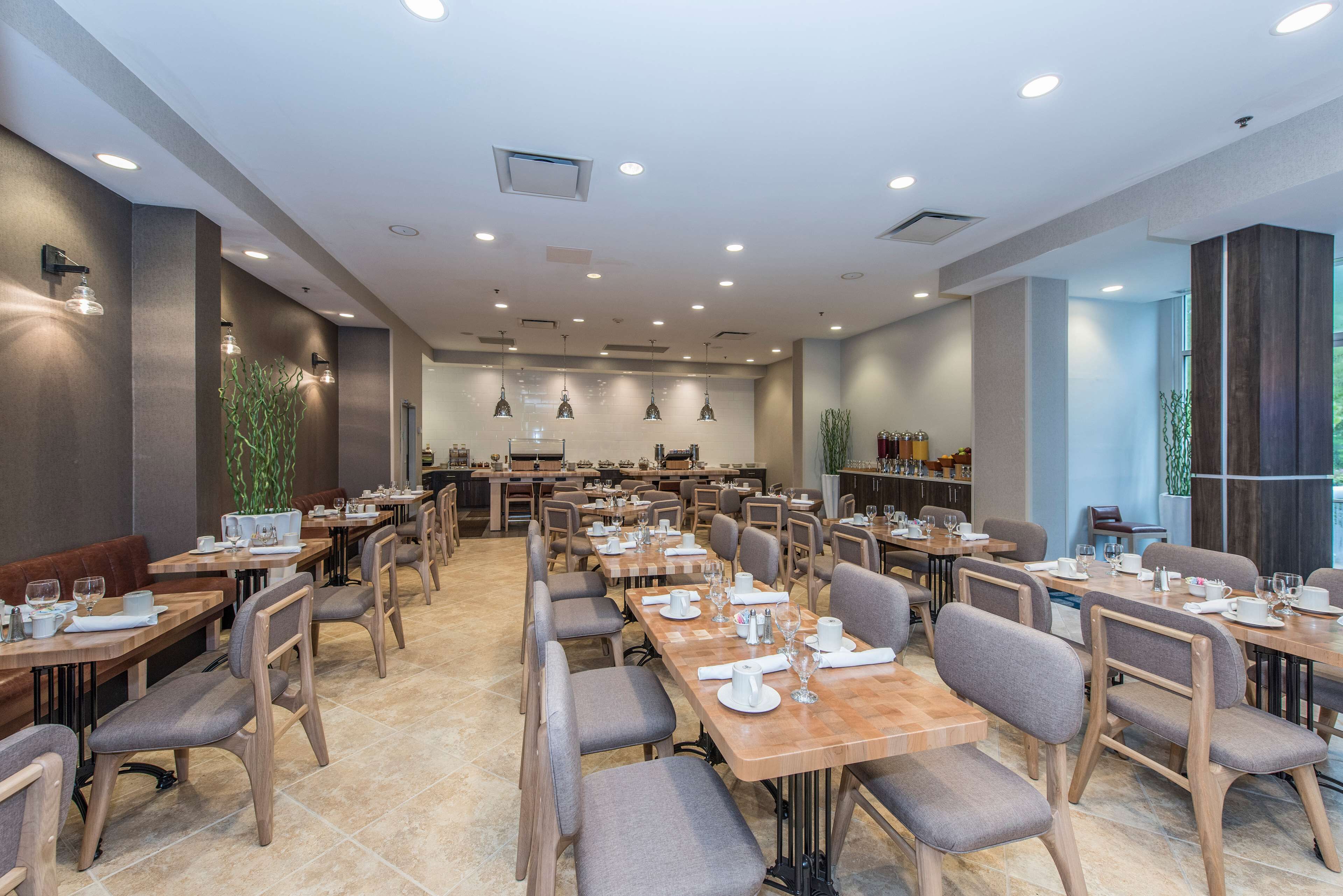 A spacious dining area with multiple tables and chairs, equipped with table settings and ambient lighting.