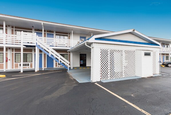 A motel with a central staircase, a covered outdoor area, and a parking lot. - Motel 6 Parkersburg, WV (Parkersburg)