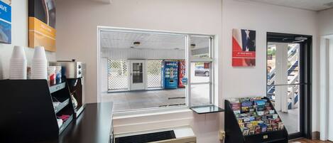 A reception area with a counter, a display of magazines, and a view of the outside.