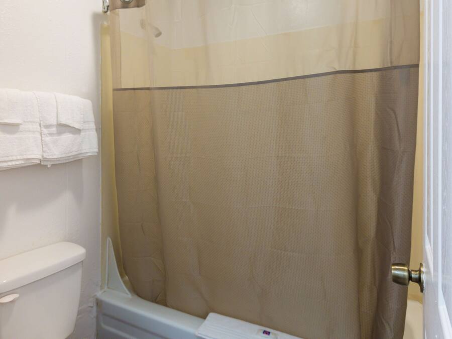 A bathroom with a toilet, a shower curtain, and a towel hanging on the wall.