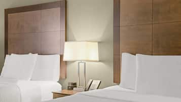 A hotel room with two beds, a nightstand, a lamp, and a telephone.