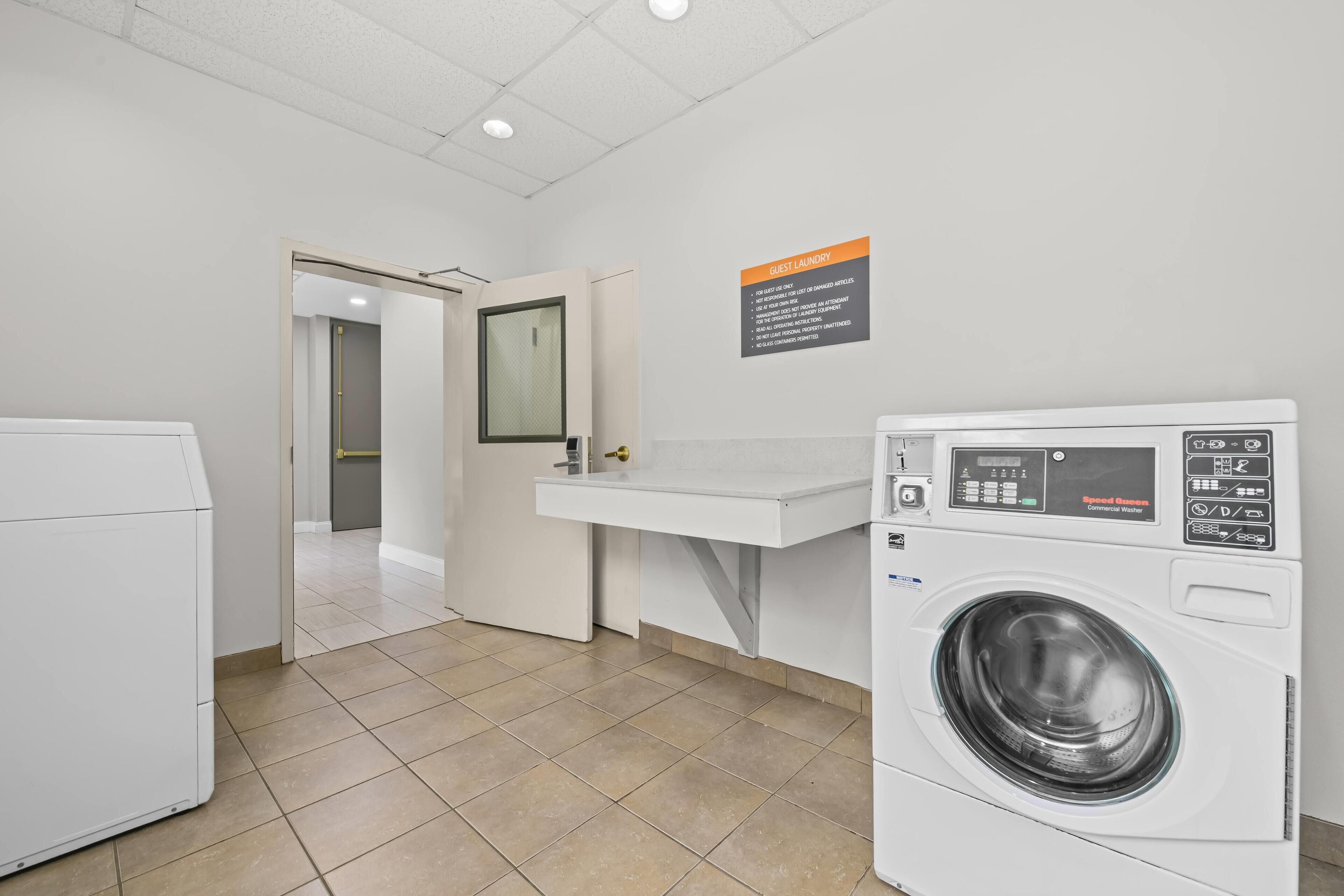 A laundry area with a washing machine, a sink, and a mirror.