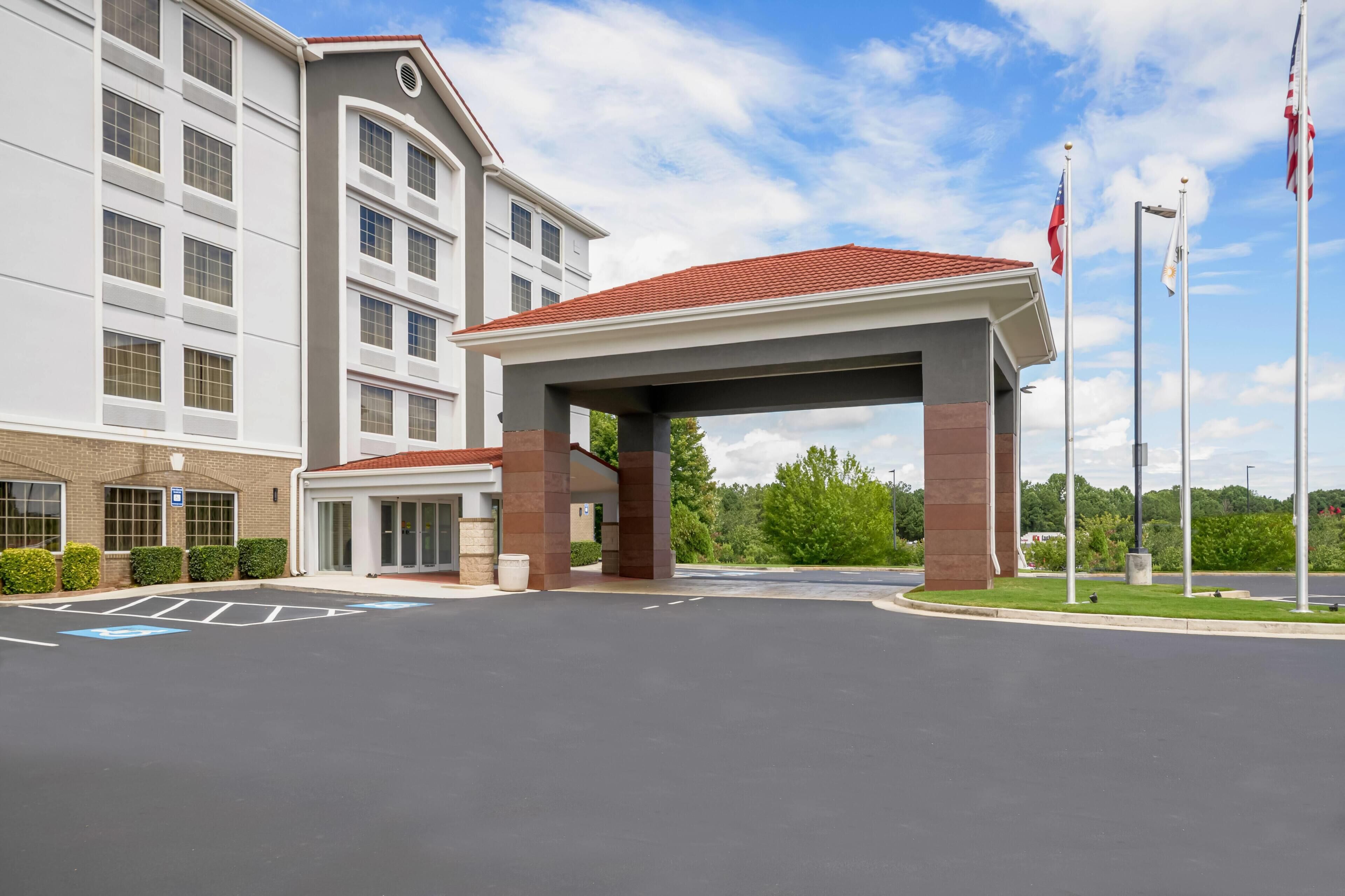 L’entrée d’un hôtel, avec un espace d’attente abrité, de nombreux étages et des drapeaux.