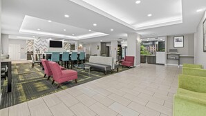 A spacious lobby with a dining area, seating arrangements, and a kitchen in the background.