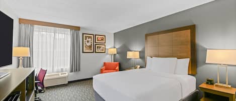 Habitación de hotel con una cama grande, dos mesitas de noche con lámparas, un escritorio con silla y un televisor.